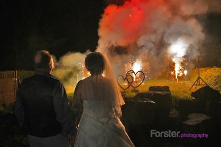 Brautpaar am Hochzeitstag schaut sich bei Nacht ein Feuerwerk während der Feier an