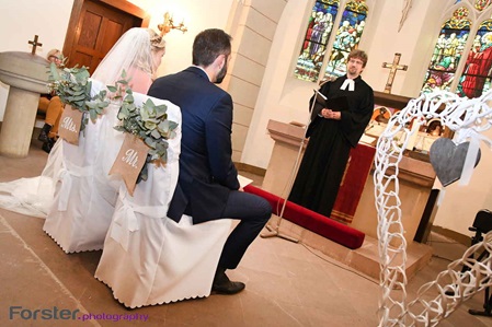 Ein Brautpaar sitzt an der Hochzeit in der Kirche am Altar vor dem Pastor und blickt gemeinsam nach vorne